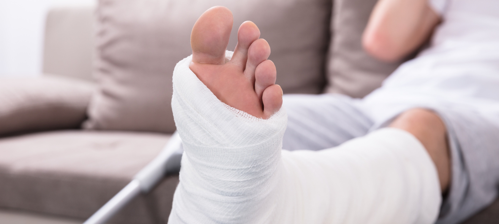 Mann mit eingegipsten sitzt auf Sofa Mann mit eingegipsten sitzt auf Sofa